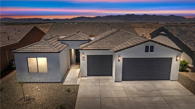 6183 S Lago Grande Dr, Fort Mohave, AZ 86426 - view of front facade featuring an attached garage, a mountain view, a tiled roof, driveway, and stucco siding