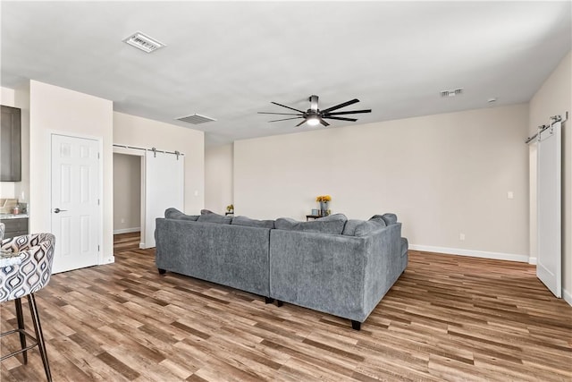 6183 S Lago Grande Dr, Fort Mohave, AZ 86426 - living room featuring a barn door, wood finished floors, a ceiling fan, and baseboards