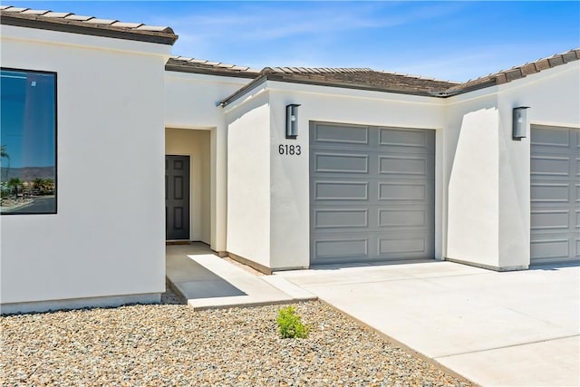 6183 S Lago Grande Dr, Fort Mohave, AZ 86426 - property entrance with an attached garage, stucco siding, a tiled roof, and concrete driveway