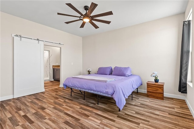 6183 S Lago Grande Dr, Fort Mohave, AZ 86426 - bedroom featuring a barn door, wood finished floors, baseboards, connected bathroom, and ceiling fan