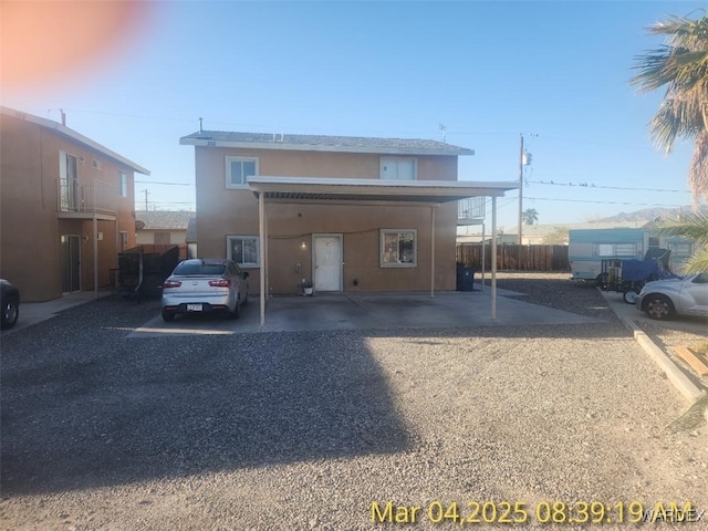 view of front of property featuring a carport, fence, and stucco siding