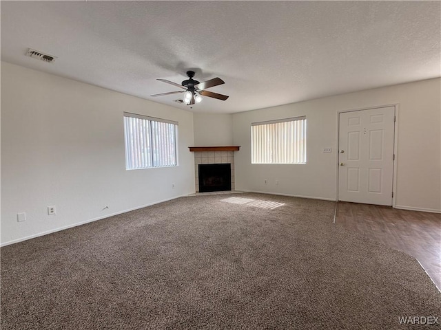 unfurnished living room featuring a ceiling fan, a wealth of natural light, visible vents, and a textured ceiling