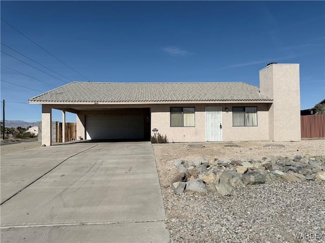 ranch-style home featuring driveway, a tiled roof, an attached garage, fence, and stucco siding