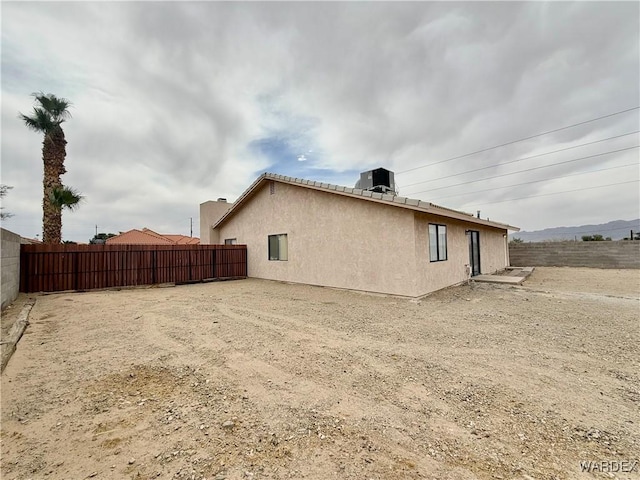 view of side of property featuring central air condition unit, fence, and stucco siding