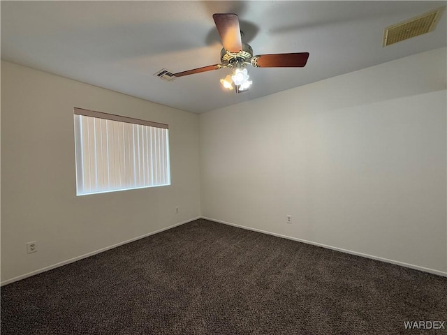 spare room with dark colored carpet, visible vents, and baseboards