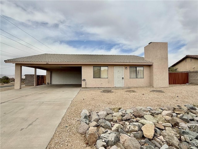 single story home with an attached garage, a tile roof, fence, concrete driveway, and stucco siding