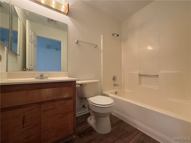 bathroom with visible vents, toilet, wood finished floors, vanity, and washtub / shower combination