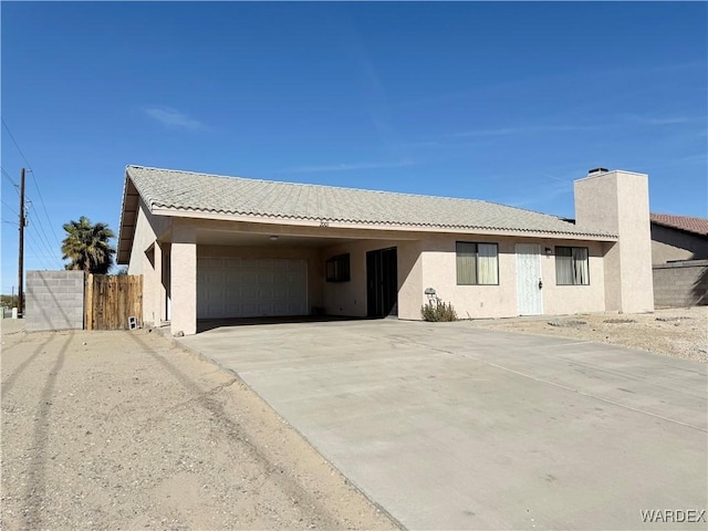 single story home featuring driveway, a tile roof, an attached garage, fence, and stucco siding