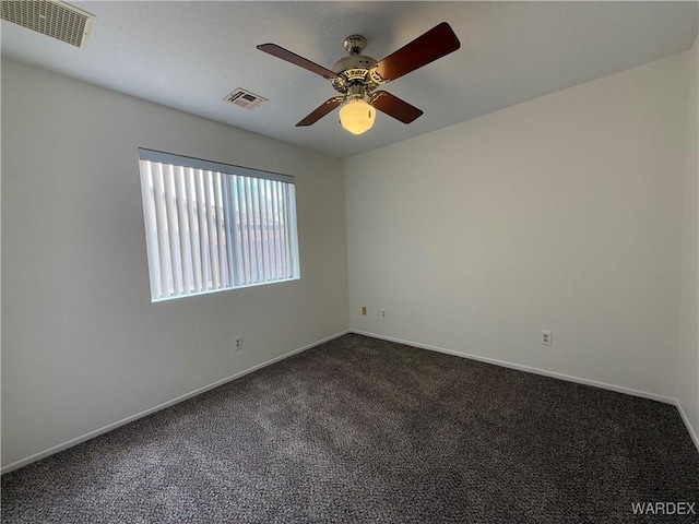 unfurnished room featuring dark carpet, visible vents, and baseboards