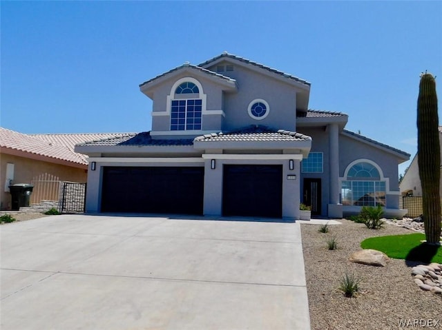 mediterranean / spanish-style house with driveway, a tile roof, a garage, and stucco siding