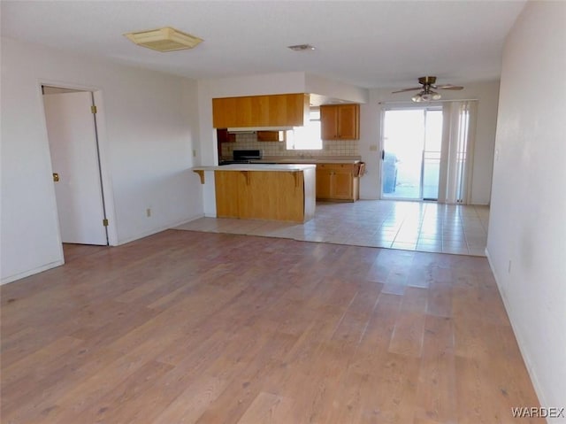 kitchen featuring open floor plan, light countertops, light wood-type flooring, and a peninsula