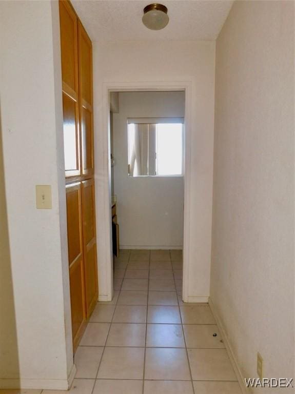 hallway featuring baseboards and light tile patterned flooring