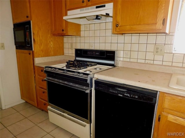 kitchen featuring decorative backsplash, brown cabinets, under cabinet range hood, light countertops, and black appliances