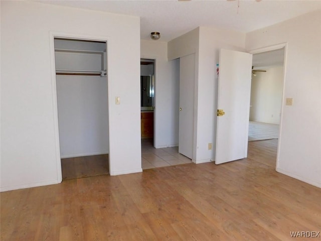 unfurnished bedroom with light wood-style floors, ensuite bath, and baseboards