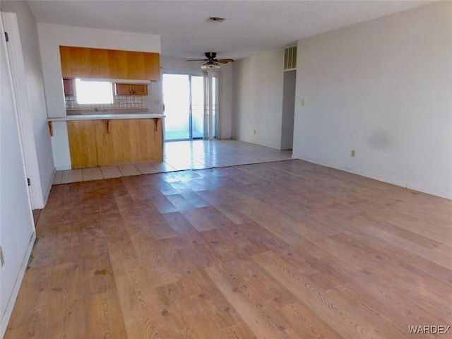 kitchen with a peninsula, visible vents, open floor plan, light countertops, and light wood-type flooring