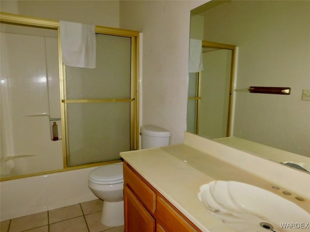 bathroom with combined bath / shower with glass door, vanity, toilet, and tile patterned floors