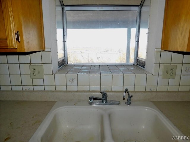 interior details with tasteful backsplash, tile counters, and a sink