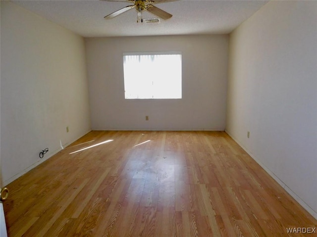 empty room featuring a ceiling fan, light wood-type flooring, and visible vents