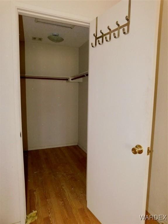 walk in closet with wood finished floors