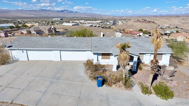 view of front of home featuring an attached garage, a mountain view, concrete driveway, roof with shingles, and a residential view