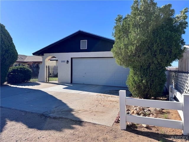 exterior space featuring fence, stucco siding, a garage, and concrete driveway
