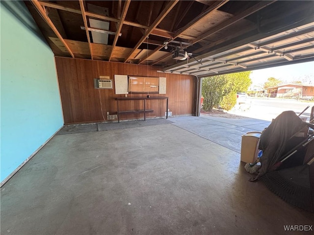 garage with wood walls, an AC wall unit, and a garage door opener