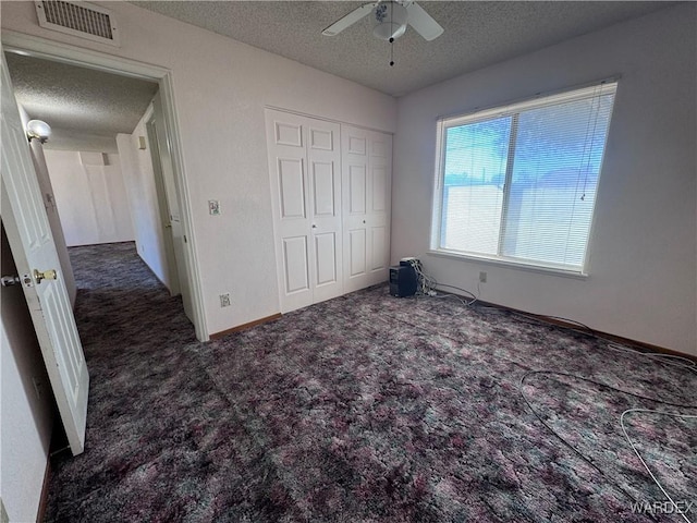 unfurnished bedroom with visible vents, a closet, a ceiling fan, carpet, and a textured ceiling