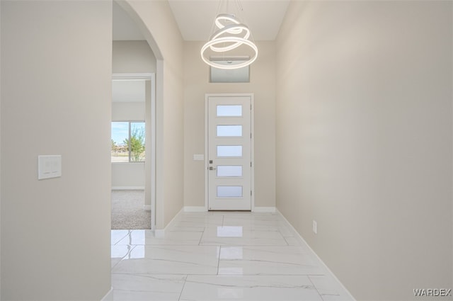 entryway with arched walkways, marble finish floor, and baseboards