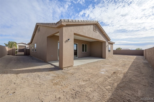 back of house featuring a patio, a fenced backyard, a tiled roof, and stucco siding