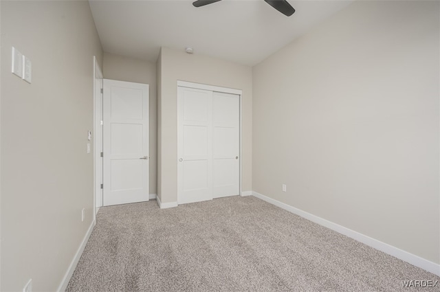 unfurnished bedroom featuring carpet floors, a closet, baseboards, and a ceiling fan