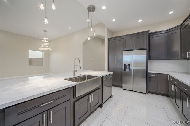 kitchen featuring dark brown cabinetry, stainless steel appliances, a sink, light countertops, and pendant lighting