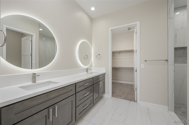 bathroom with marble finish floor, a sink, baseboards, and double vanity