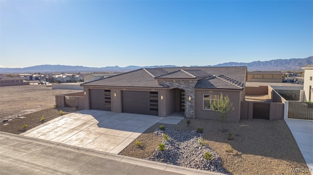 view of front of property with an attached garage, a mountain view, concrete driveway, and stucco siding