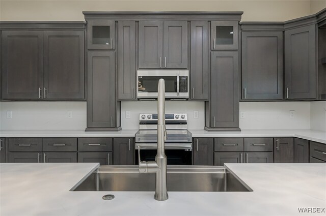 kitchen with glass insert cabinets, stainless steel appliances, and light countertops