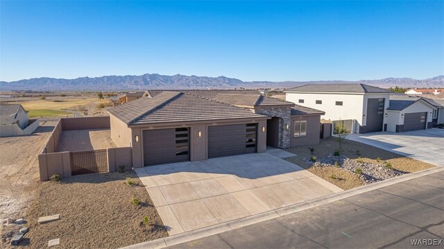 view of front facade with a garage, fence, a mountain view, and stucco siding