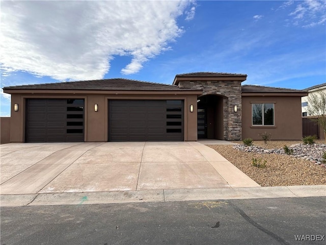 prairie-style home featuring a garage, stone siding, driveway, and stucco siding