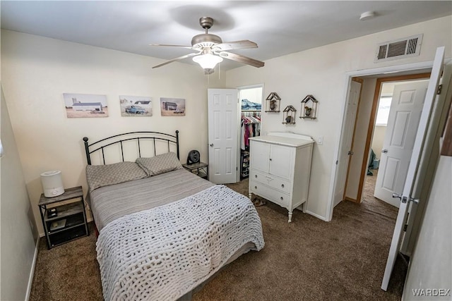 bedroom featuring a closet, visible vents, a spacious closet, a ceiling fan, and carpet flooring