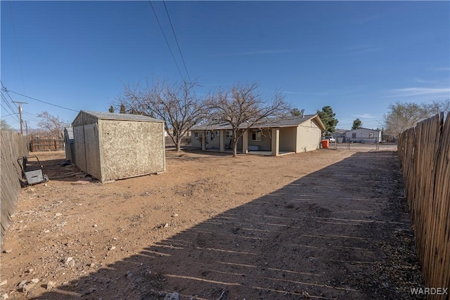 view of yard with a storage shed, a fenced backyard, and an outbuilding