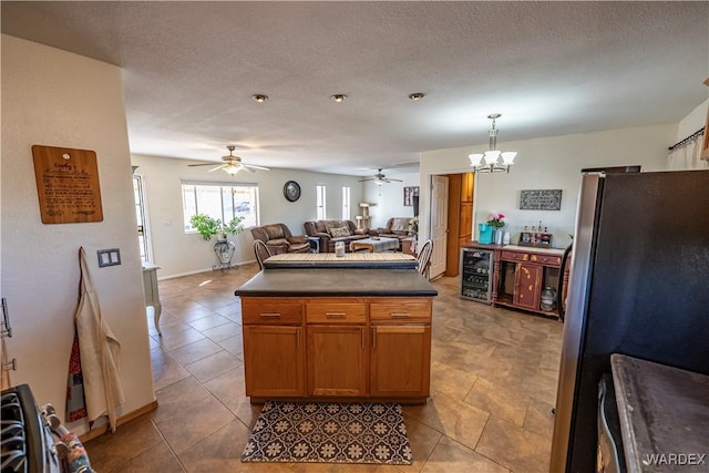 kitchen featuring a textured ceiling, beverage cooler, open floor plan, freestanding refrigerator, and dark countertops