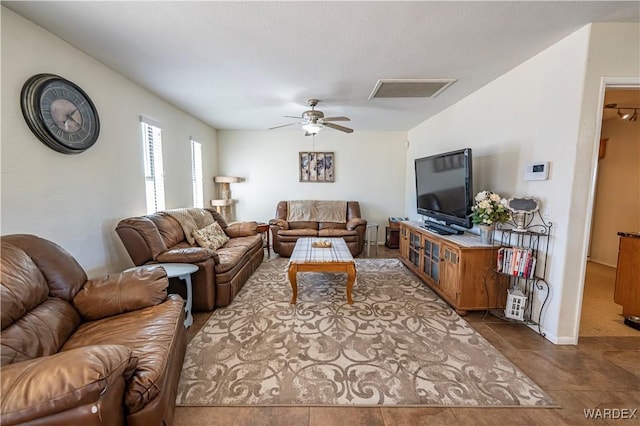 living room with dark tile patterned flooring, visible vents, and ceiling fan