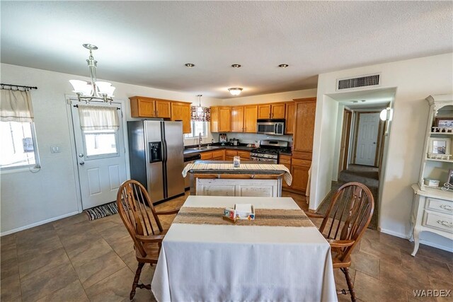 dining area with baseboards, visible vents, a chandelier, and a wealth of natural light