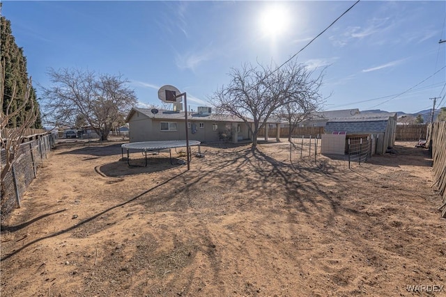 view of yard with an outbuilding, a trampoline, and a fenced backyard