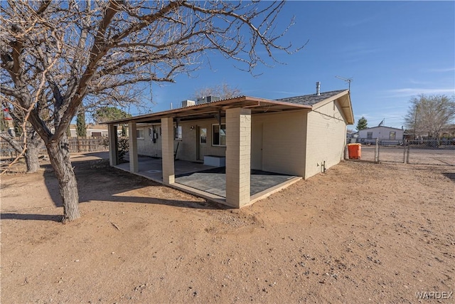 back of property with a gate, brick siding, fence, and a patio