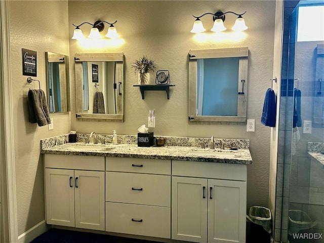 bathroom featuring double vanity, a shower stall, and a sink