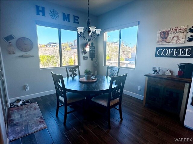 dining area featuring dark wood-style floors, a chandelier, and baseboards