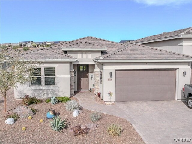 view of front facade featuring decorative driveway, an attached garage, and stucco siding