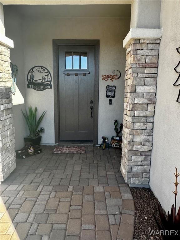 view of exterior entry with a porch and stucco siding