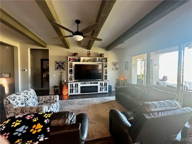 living area with beam ceiling, a fireplace, ceiling fan, and wood finished floors