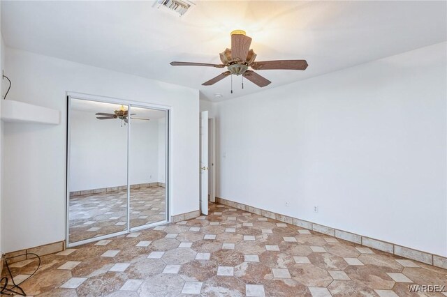 unfurnished bedroom featuring baseboards, visible vents, ceiling fan, and a closet