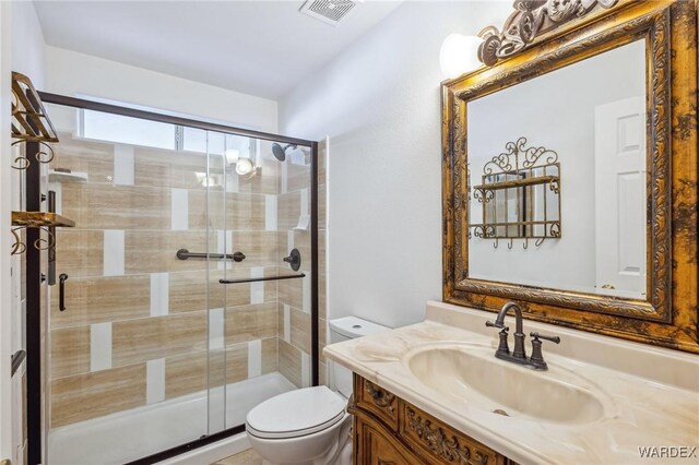 bathroom featuring toilet, a stall shower, vanity, and visible vents